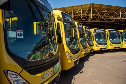 Vários ônibus urbanos amarelos estacionados em um terminal de transporte coletivo.