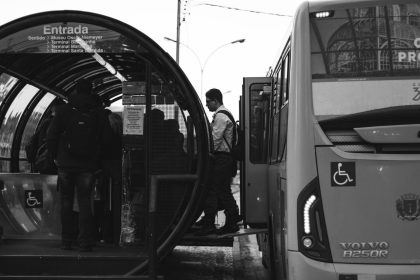 Passageiros embarcam em um ônibus em uma estação de transporte.