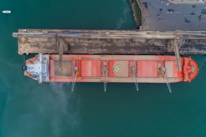 Vista aérea de um navio de carga atracado no porto de São Francisco do Sul, com a operação marítima ao redor.